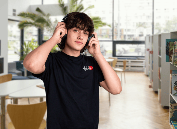 Un jeune homme tient ses écouteurs dans une bibliothèque, se préparant à écouter une session d'étude en ligne avec La 2e Classe. Son geste indique une fusion de concentration traditionnelle et de technologie moderne, essentielle pour l'apprentissage contemporain.