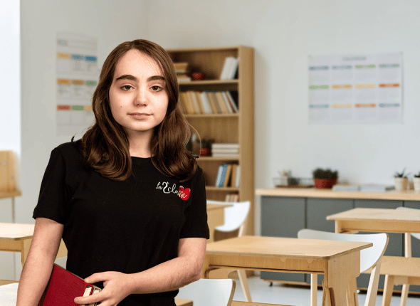 Une adolescente de secondaire 4, sérieuse et concentrée, participe à une session d'apprentissage en classe avec La 2e Classe. Assise dans une salle d'étude calme et organisée, elle est absorbée par les matériaux pédagogiques devant elle, reflétant son engagement envers son éducation supérieure.