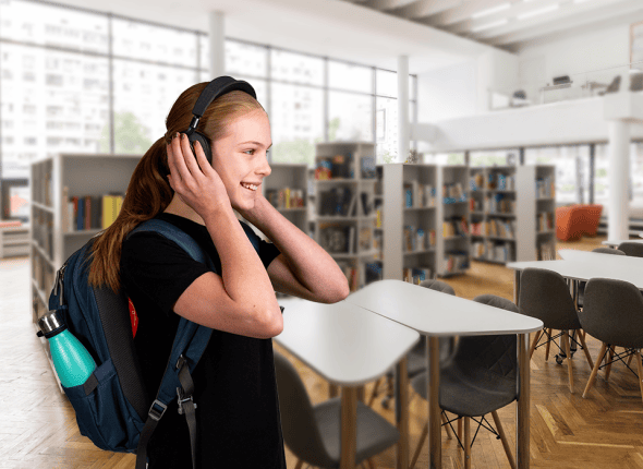 Une adolescente écoute de la musique avec des écouteurs tout en étant assise dans une bibliothèque calme. Son expression détendue et concentrée reflète une méthode moderne d'étude qui combine relaxation et apprentissage, promue par La 2e Classe.