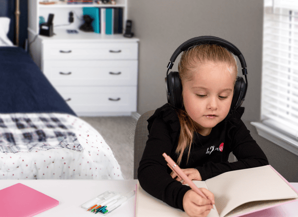 Une petite fille écrit consciencieusement dans sa chambre lors d'une session de tutorat en ligne avec La 2e Classe. Elle est concentrée sur son travail, démontrant son engagement et sa motivation pour exceller dans ses études grâce à notre support pédagogique adapté.