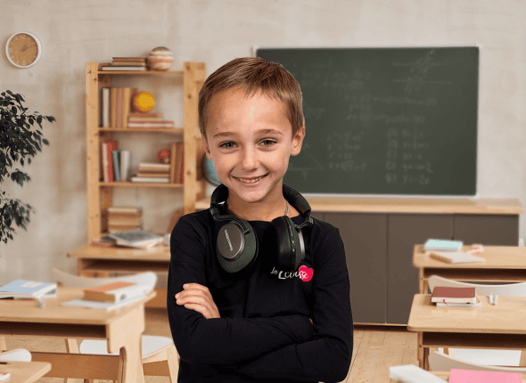 Un petit garçon souriant, assis dans une classe lumineuse, participe activement à une session de tutorat en groupe avec La 2e Classe. Ce moment capture son enthousiasme pour l'apprentissage interactif et en direct.