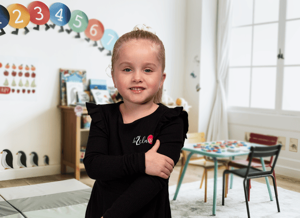 Une petite fille en classe de première année suit attentivement un cours chez La 2e Classe. Assise à son bureau dans une salle de classe colorée, elle montre son enthousiasme pour l'apprentissage dès son plus jeune âge.