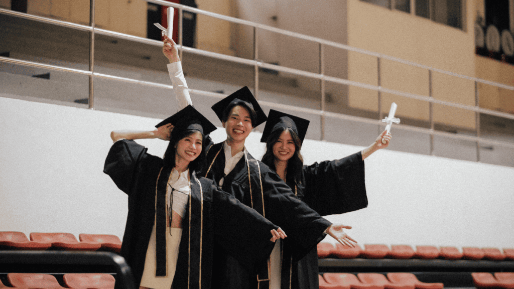 Trois étudiants en toge et mortier célèbrent leur diplôme au secondaire en ligne avec leurs certificats.