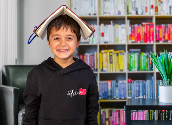 Jeune garçon souriant avec un livre sur la tête